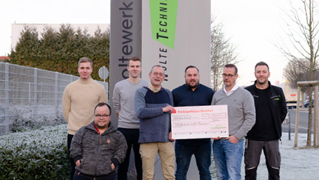 Das nolteteam unterstützt die Kinderkrebshilfe Münster erneut mit 1.000 Euro Sieben Personen vor zwei Firmenlogos, zwei Personen halten einen übergroßen Scheck.