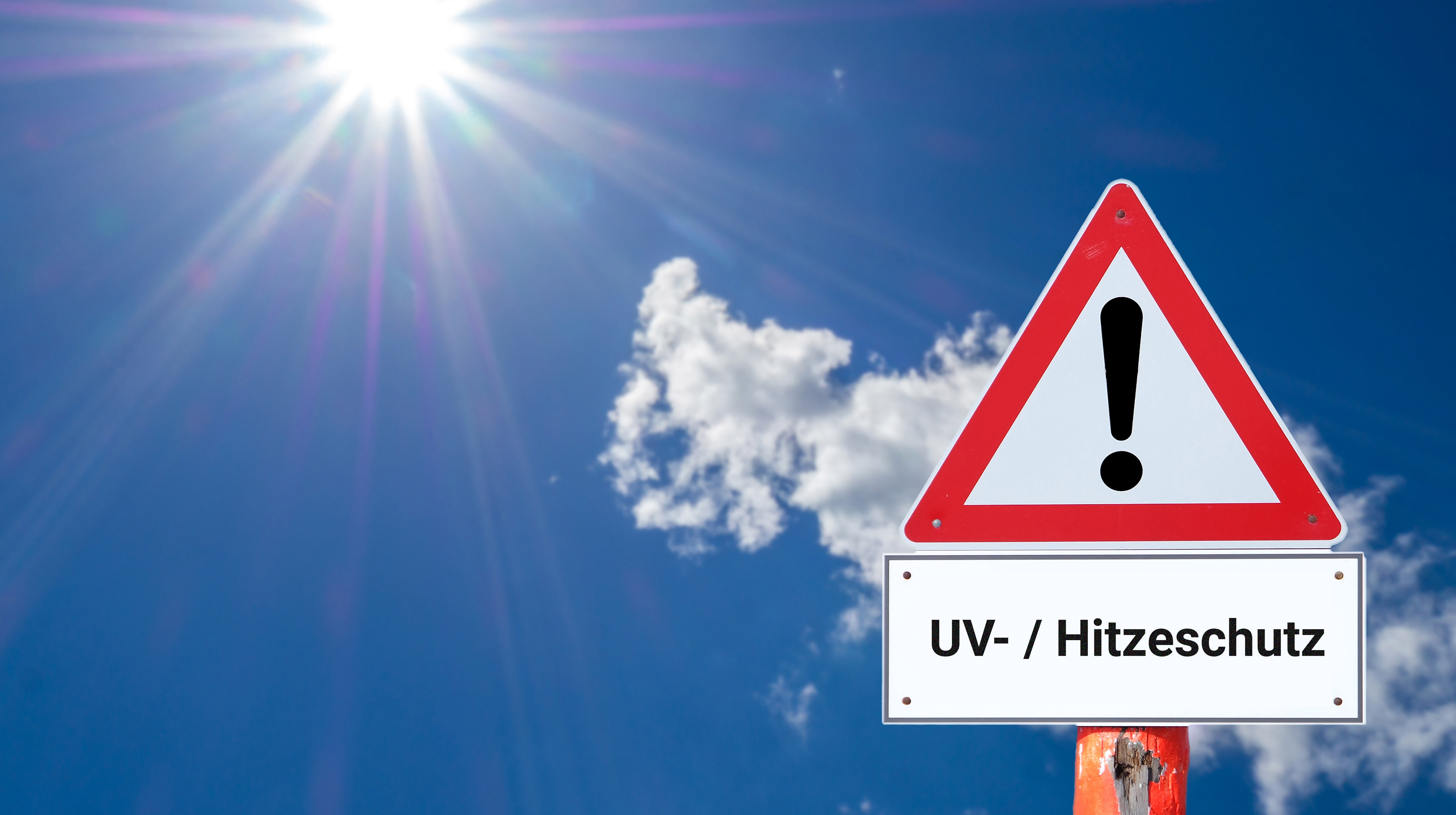 Jetzt an UV- und Hitzeschutz denken. Blauer Himmel mit gleißender Sonne und Warnschild mit Text "UV-/Hitzeschutz