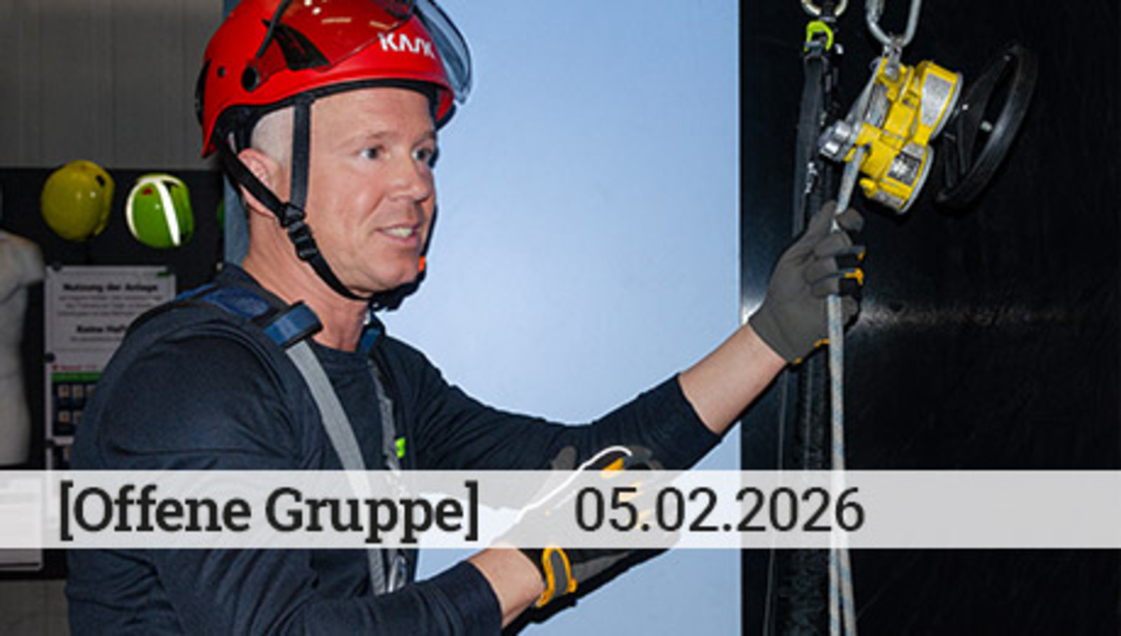 Zwei Männer in Höhensicherunggurten betrachten ein Sicherungsgerät mit einem Handrad.