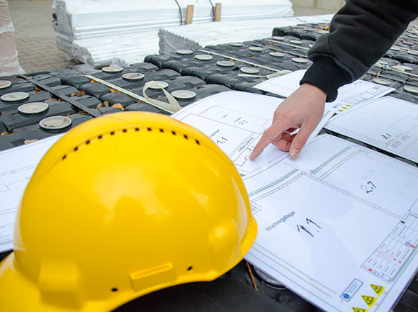 Planungsszene: Helm und Pläne auf der Baustelle
